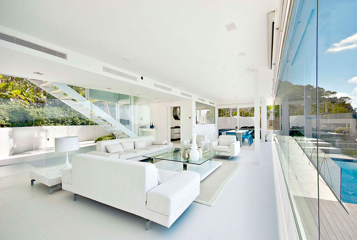 A living room with white furniture and glass table.